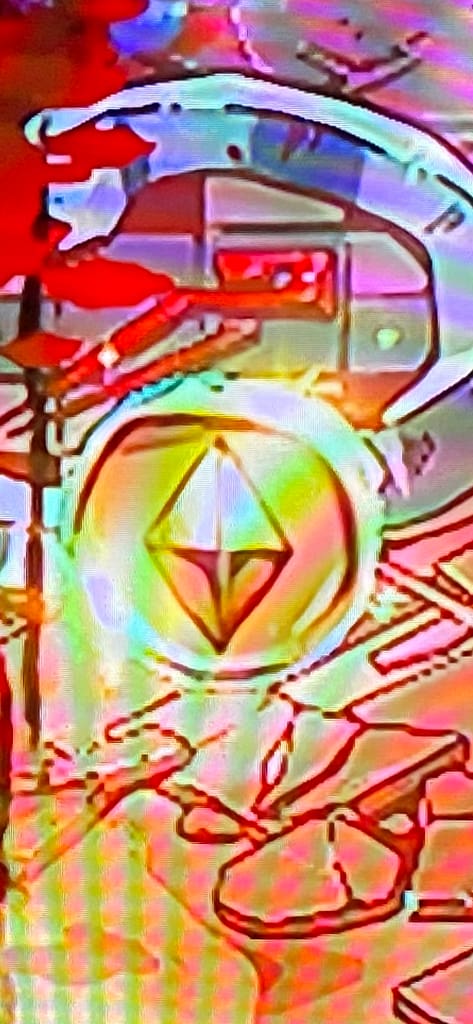 Zag next to a spinning coin showing the back is a pyramid, not the Hades symbol. Very zoomed in on the coin.