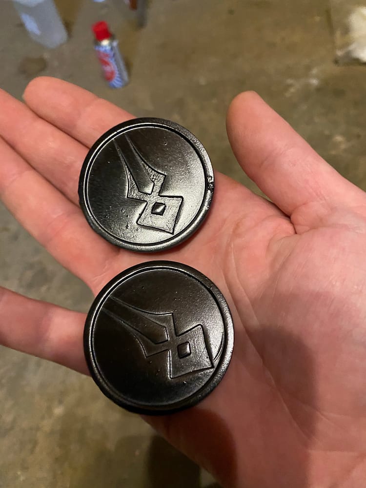 Two coins with a black glossy finish.