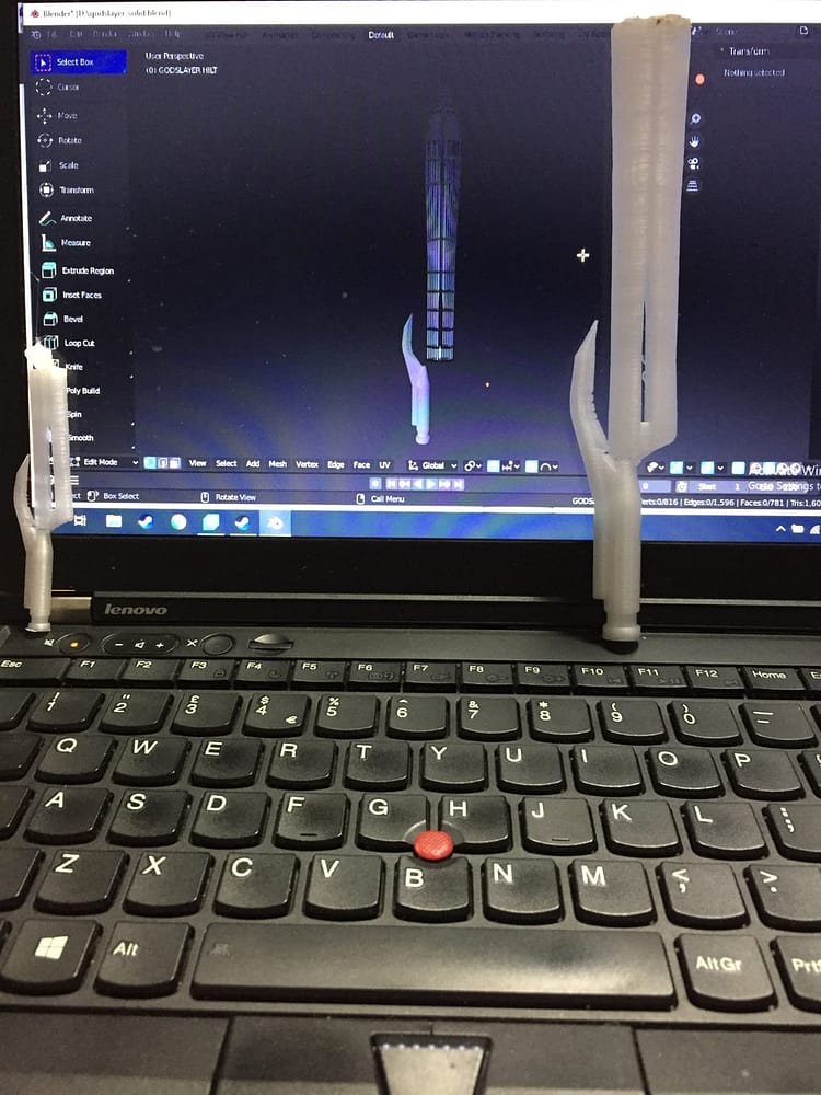 Small prototype swords next to their designs on the laptop screen.