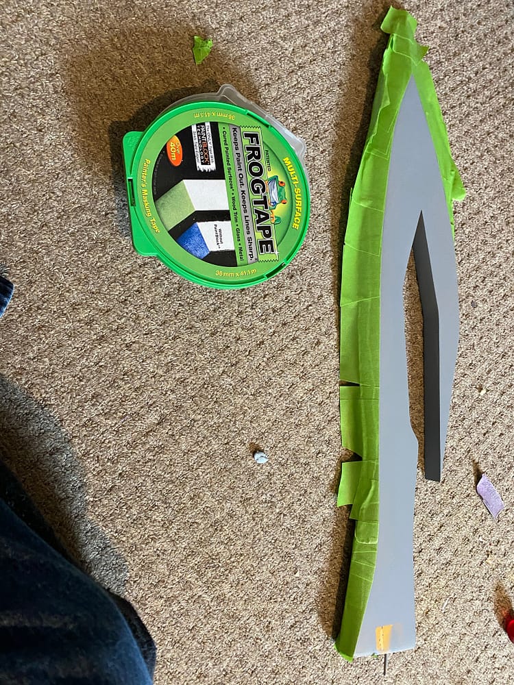 Green tape being applied to the bladed edge. Tap is green, rest of the item is primed grey. Capet definitely needs a hoover...