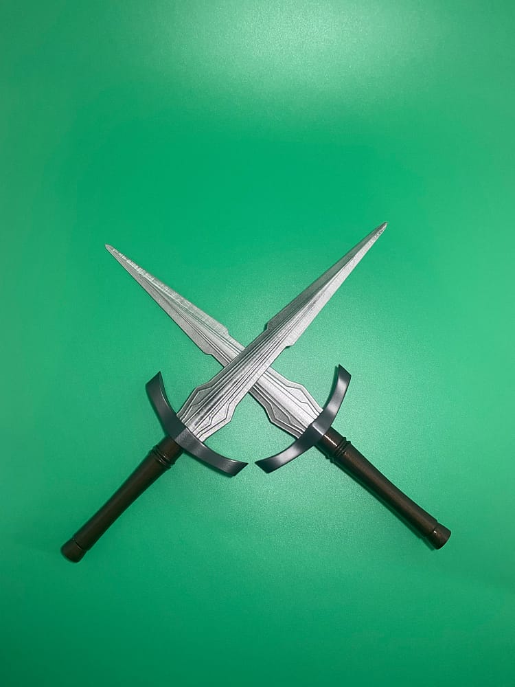 Two finished daggers in a cross on a green background.